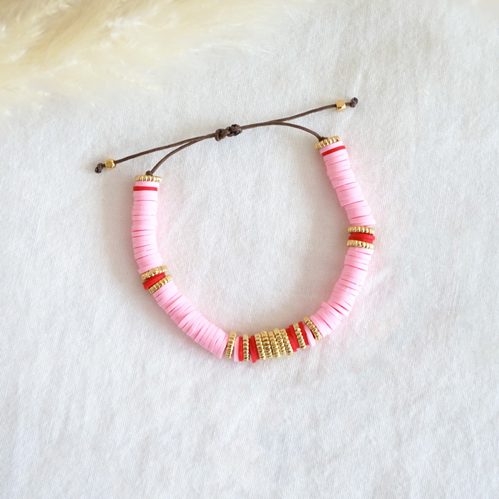 Bracelet de perles heishi rose et corail sur fil de jade marron décoré de perles dorées.